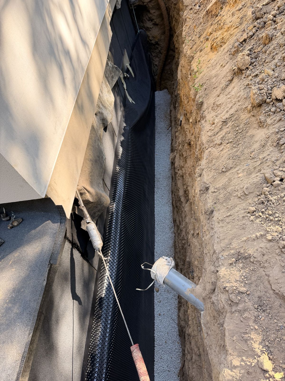 Nappe drainante à excroissances et lit de gravier avec drain en pied de mur