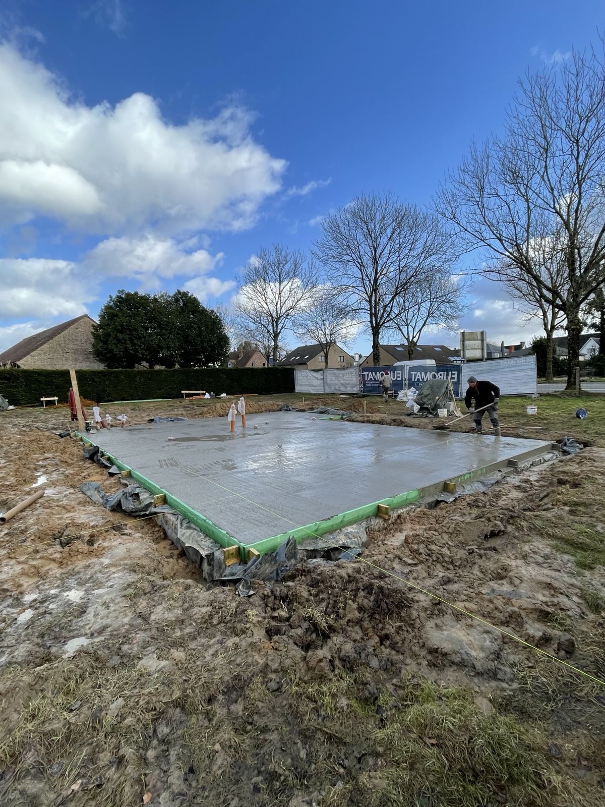 Dalle de sol en béton fraîchement coulée avec ouvrier au lissage
