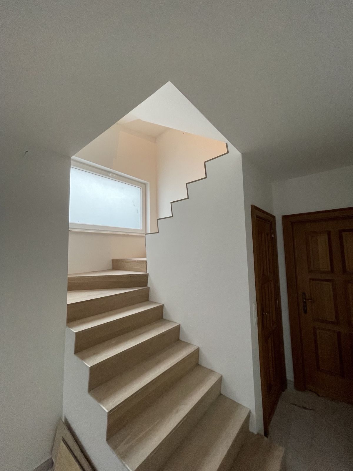 Escalier en chêne clair avec mur crénelé suivant les marches