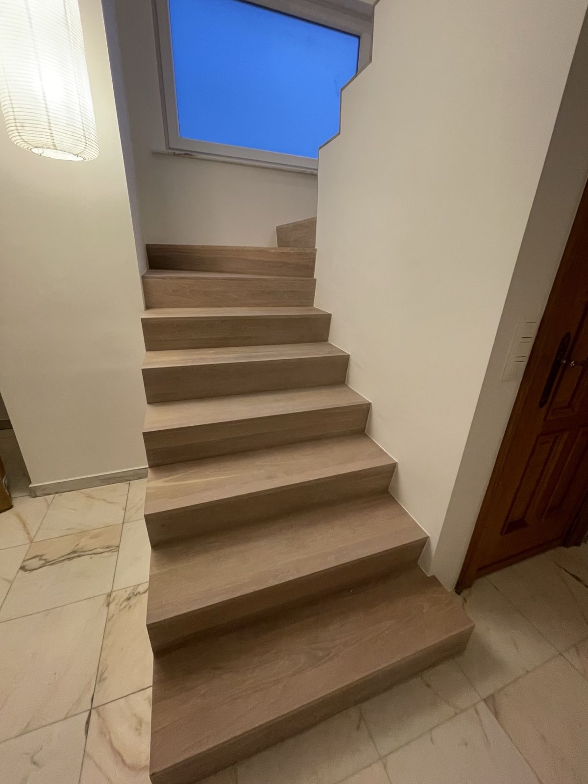 Escalier habillé en chêne au départ d'un hall carrelé