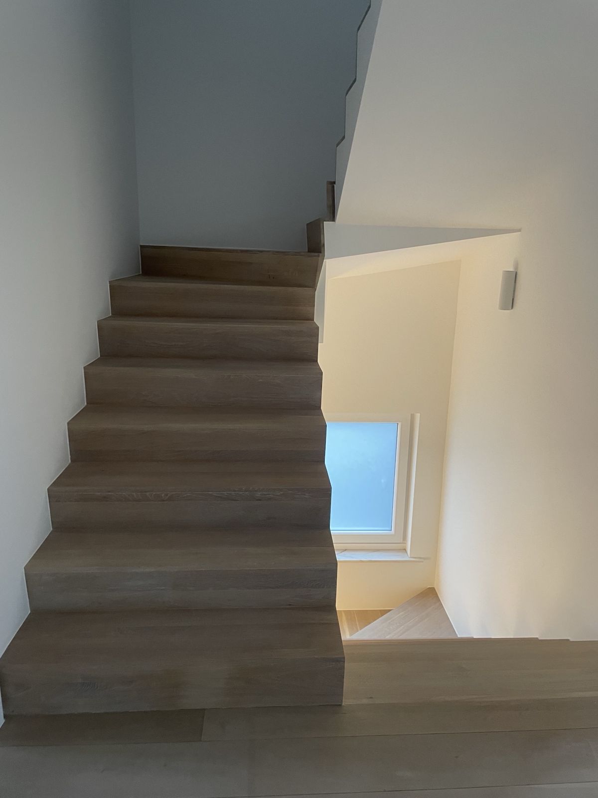 Escalier en chêne avec marches et contremarches, éclairage par applique murale