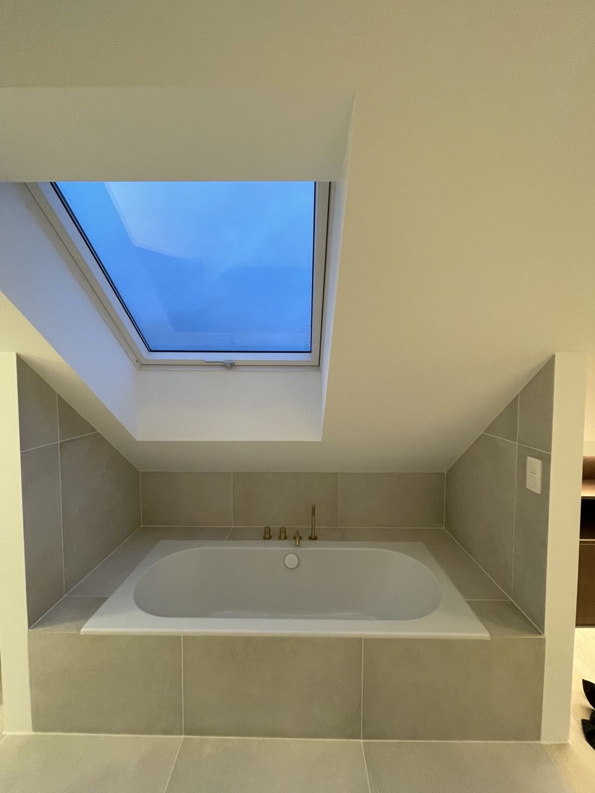 Baignoire encastrée sous fenêtre de toit dans une salle de bain sous combles