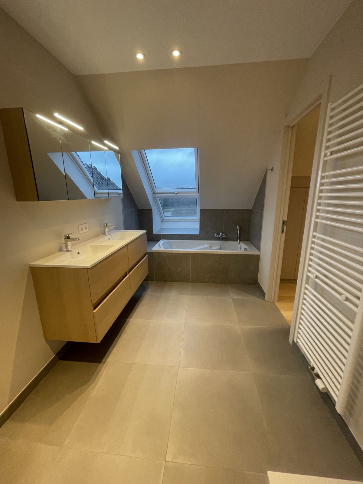 Salle de bain sous combles avec meuble en chêne et baignoire encastrée