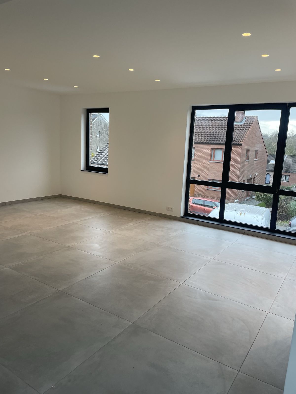 Séjour terminé à Woluwe-Saint-Pierre avec grandes baies à châssis noirs et carrelage grand format
